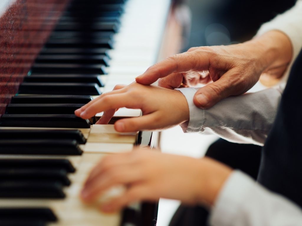 child practicing piano with instructor