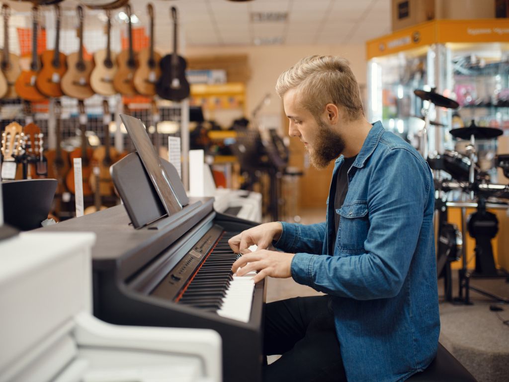 A Guide To Buying Your First Piano For Beginners 5 Musician trying to play on piano in music store