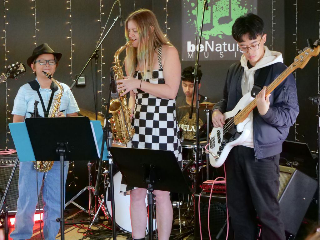 User-Inserted Students playing in a band at benatural music studio, featuring saxophones, bass guitar, and drums during a practice session